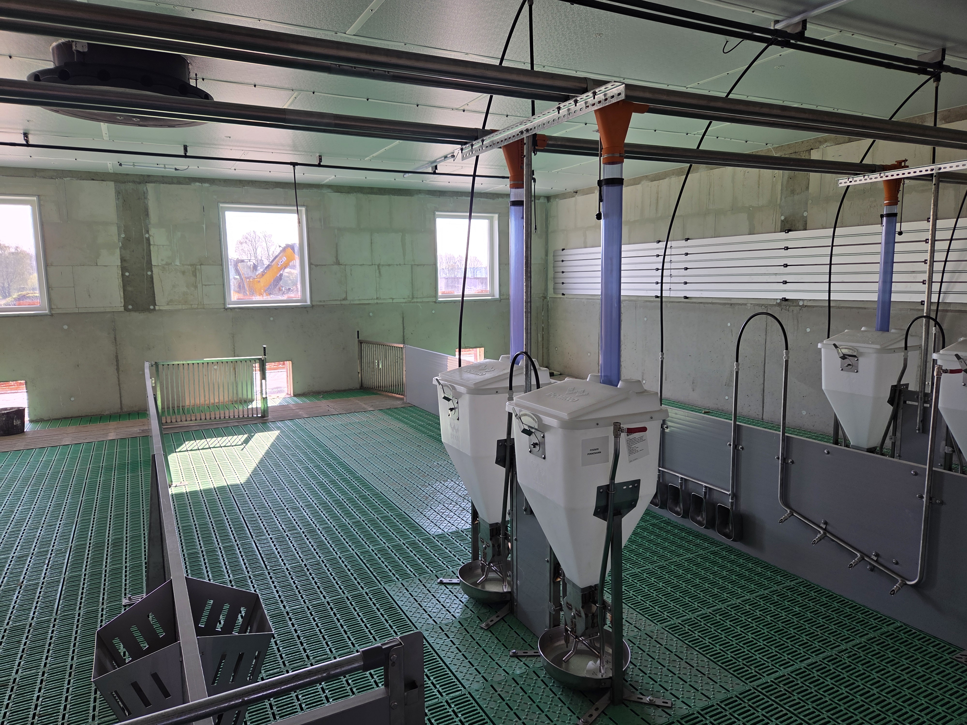 Fertig montierte Stallbucht mit Futterautomaten, Tränken und grünem Kunststoff-Spaltenboden